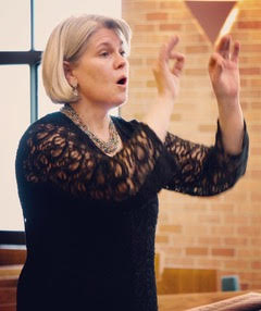 Photo of CorVoce director, Karin Barrett, conducting the choir